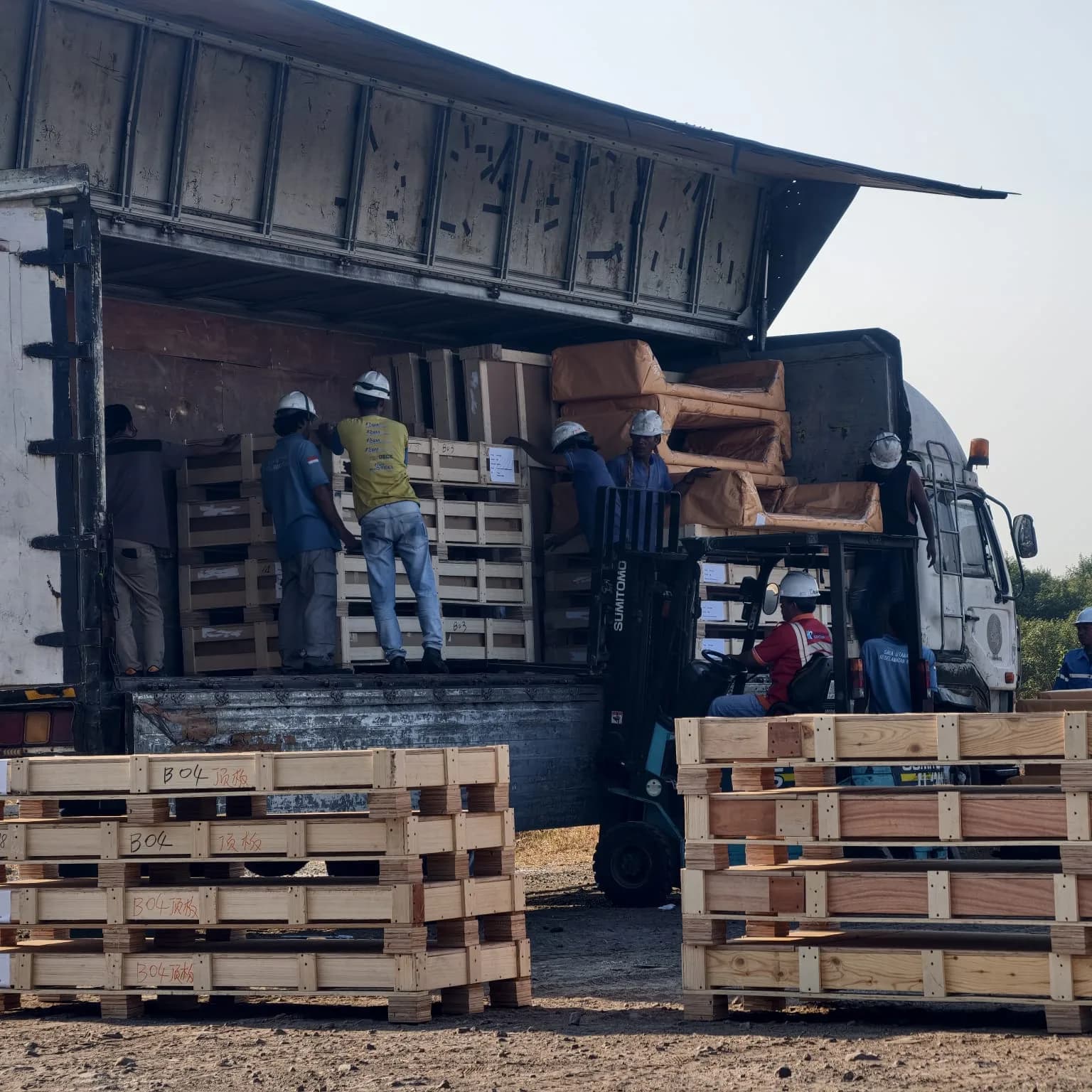 Tim dan forklift menangani peti kayu di samping truk bermuatan